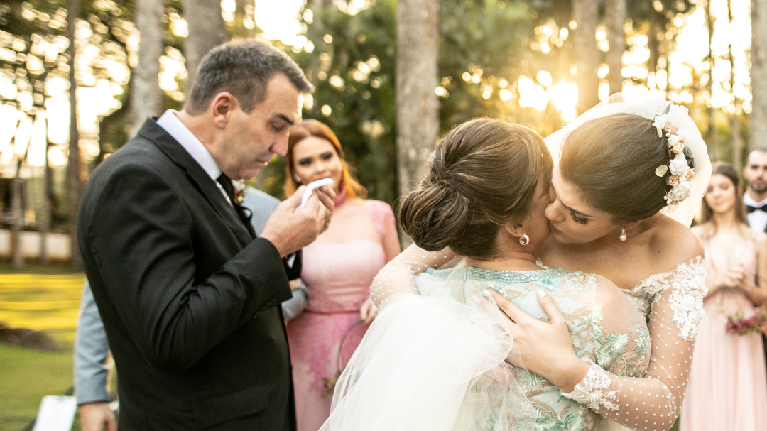 Convidados do casamento parabenizando a noiva, enquanto o noivo chora de emoção.