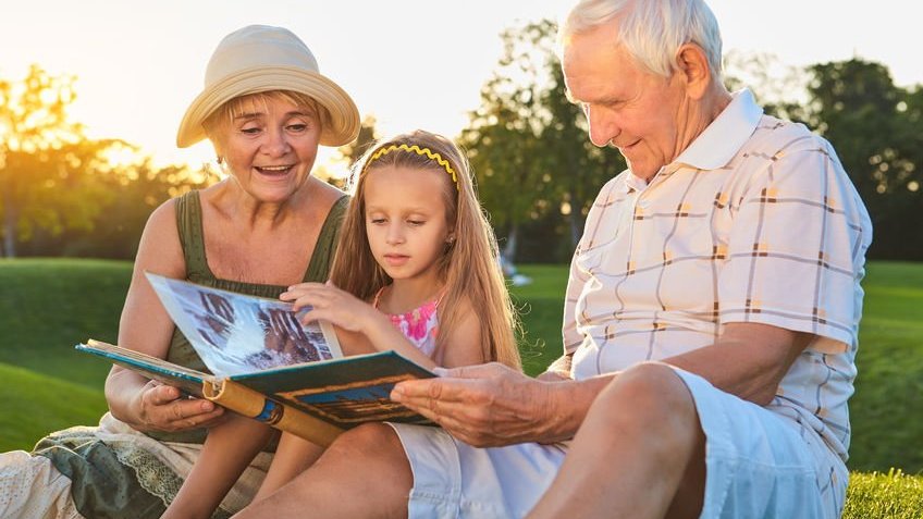 Avós com neta lendo em parque