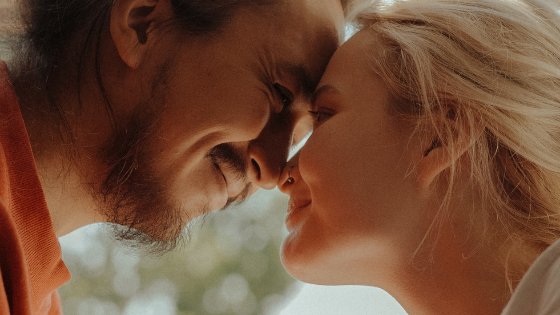 Homem e mulher sorrindo ao lado de uma janela com suas testas encostadas