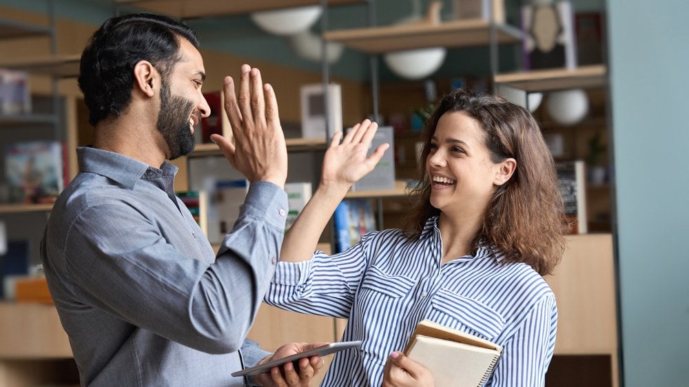 Colegas de trabalho batendo as mãos e sorrindo