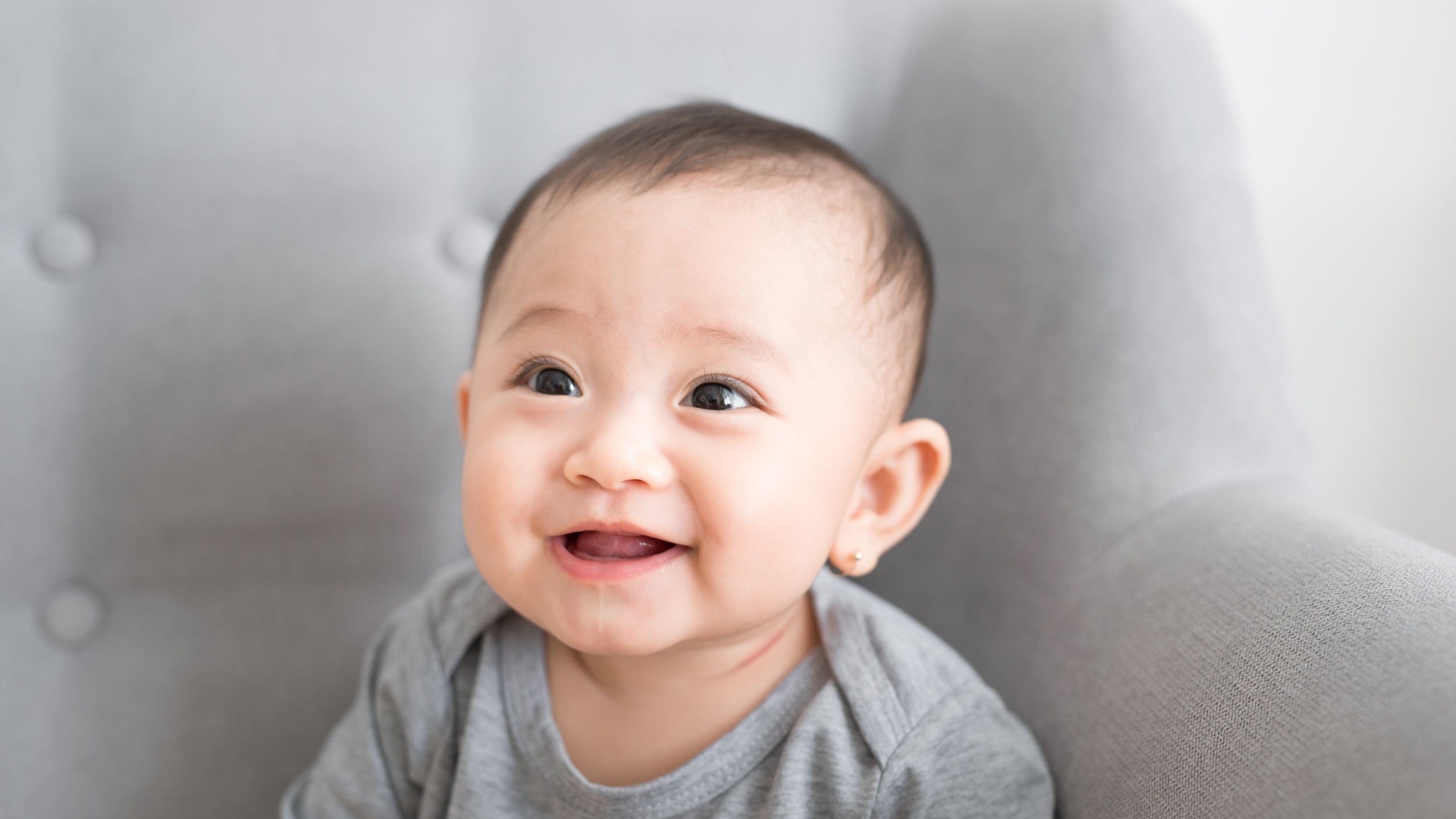 Bebê sentado em um sofá sorrindo