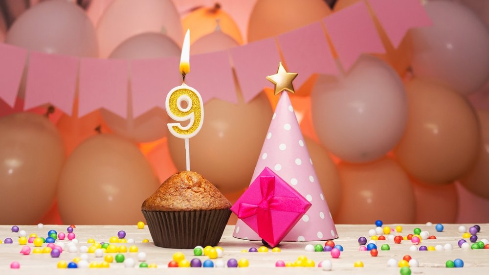 Mesa de aniversário decorada com um bolo segurando a vela de 9 anos.