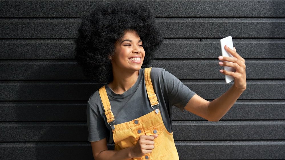 Mulher negra tirando selfie sorrindo