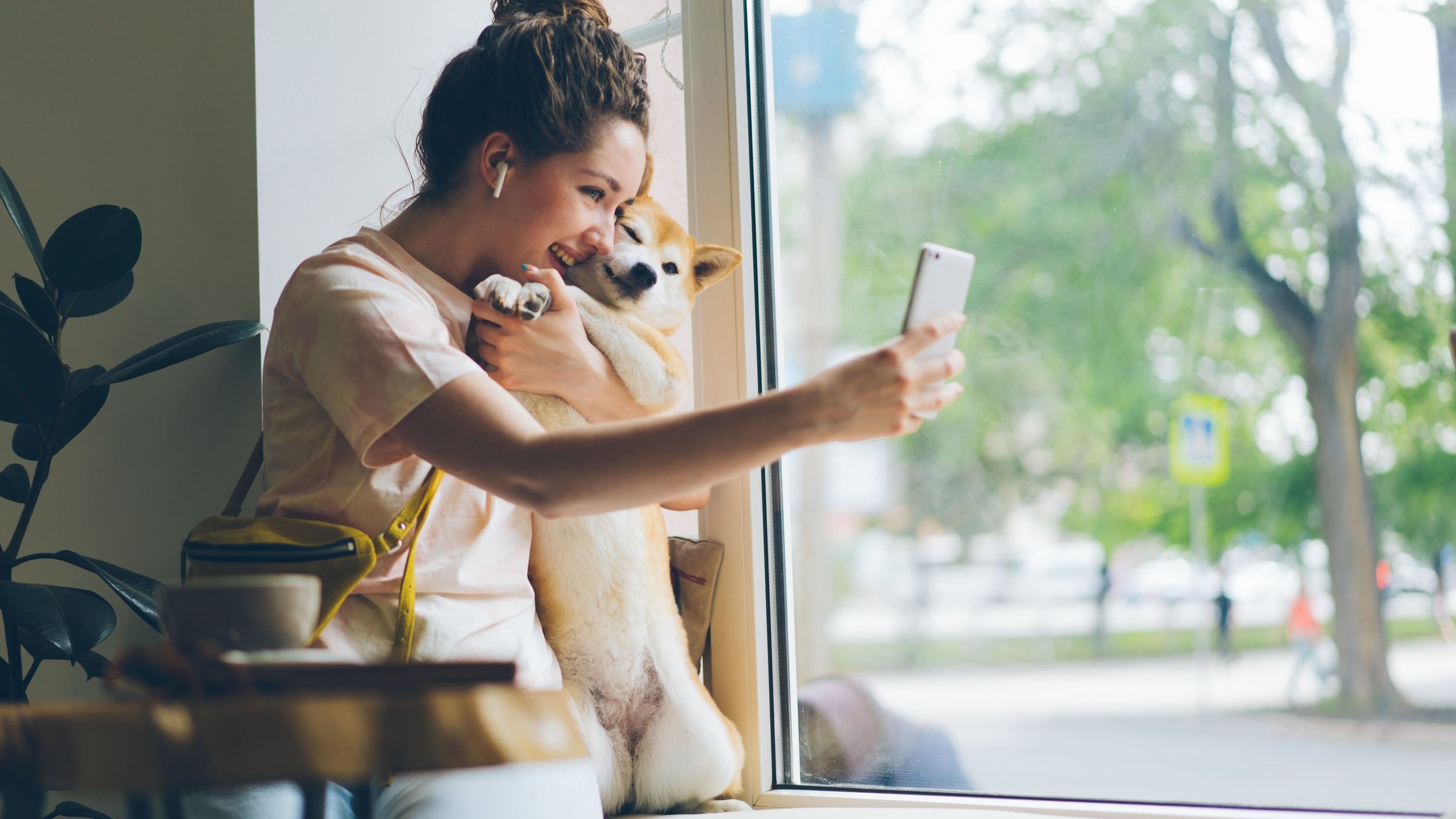 Mulher sentada à janela fotografa a si mesma com um cachorro