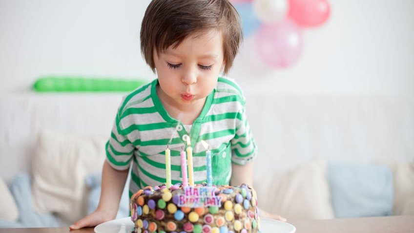 Menino soprando vela de aniversário em bolo