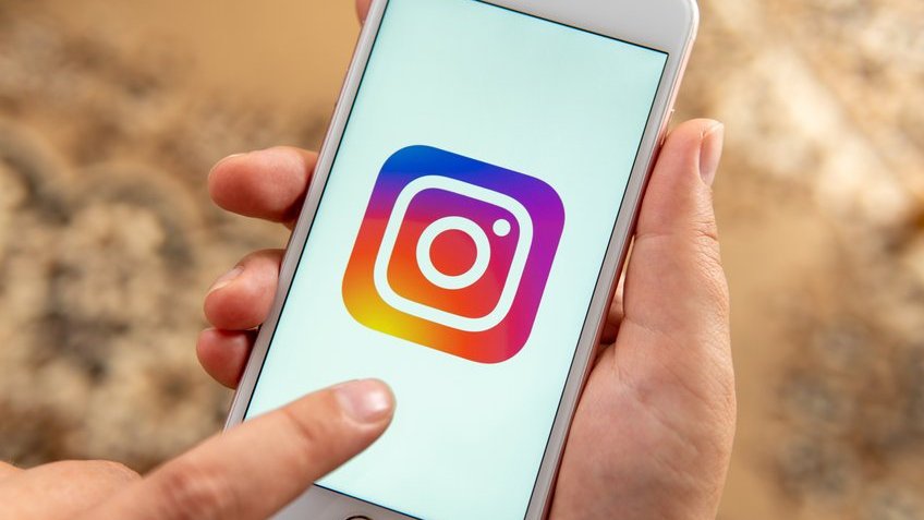 Celular branco com o logo do Instagram aberto.