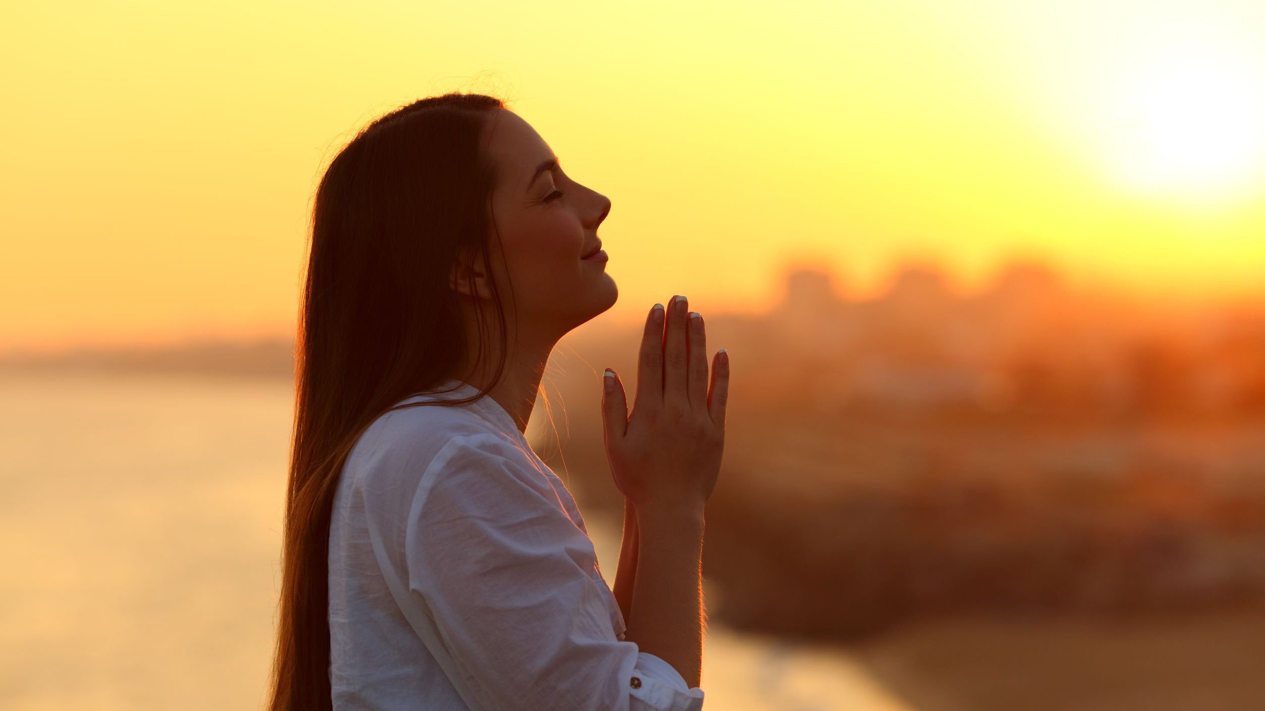 Mulher rezando ao pôr do sol