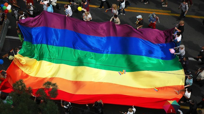 Imagem de pessoas segurando bandeira LGBT