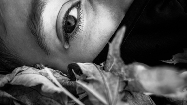Mulher chorando no chão cheio de folhas