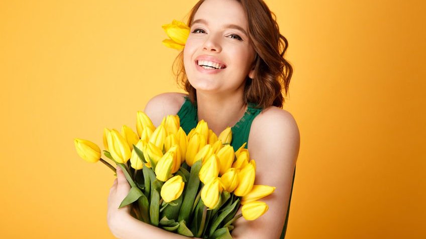 Mulher sorrindo segurando tulipas amarelas