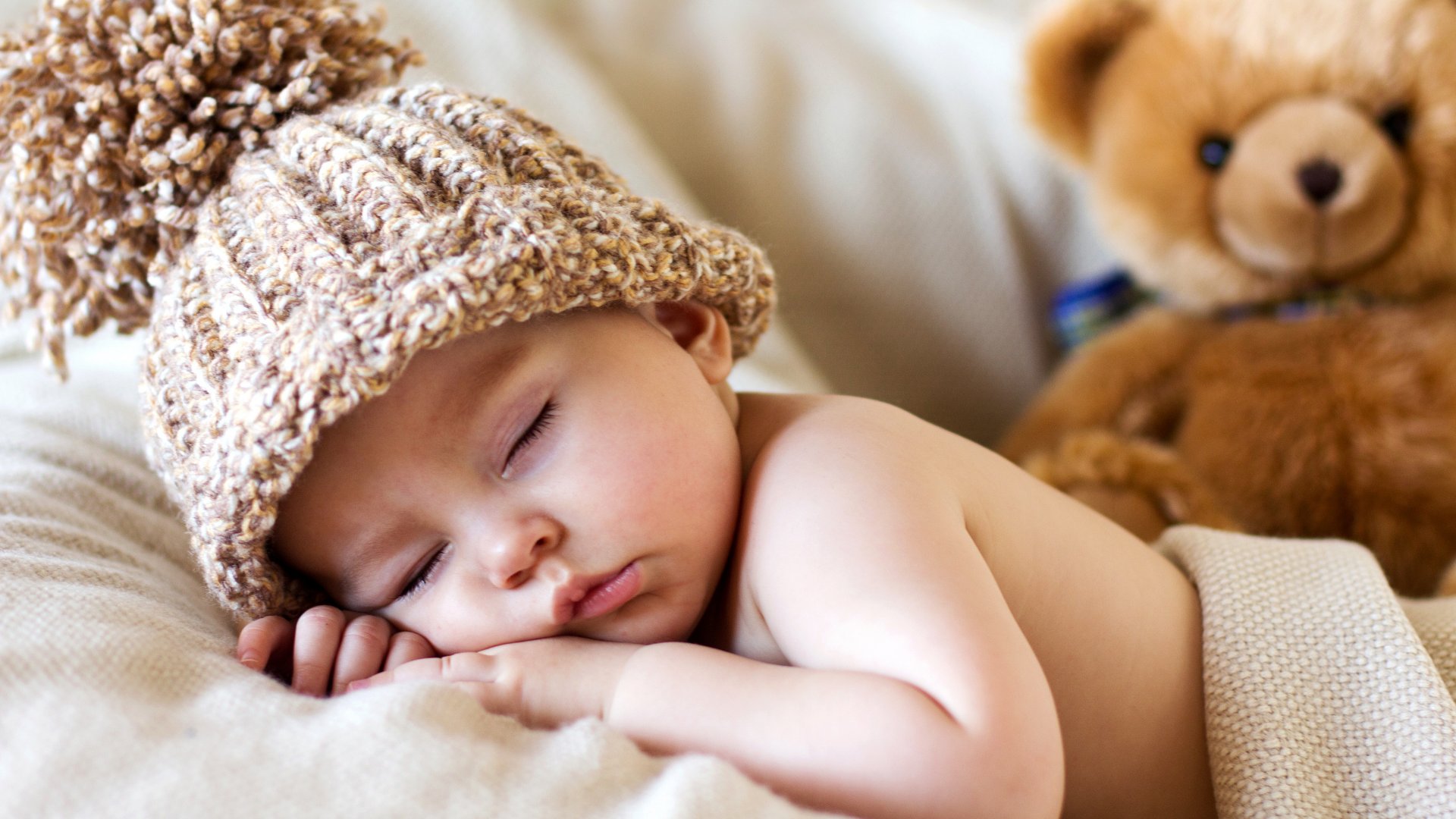 Foto de bebê de 3 meses dormindo usando uma touca bege de crochê