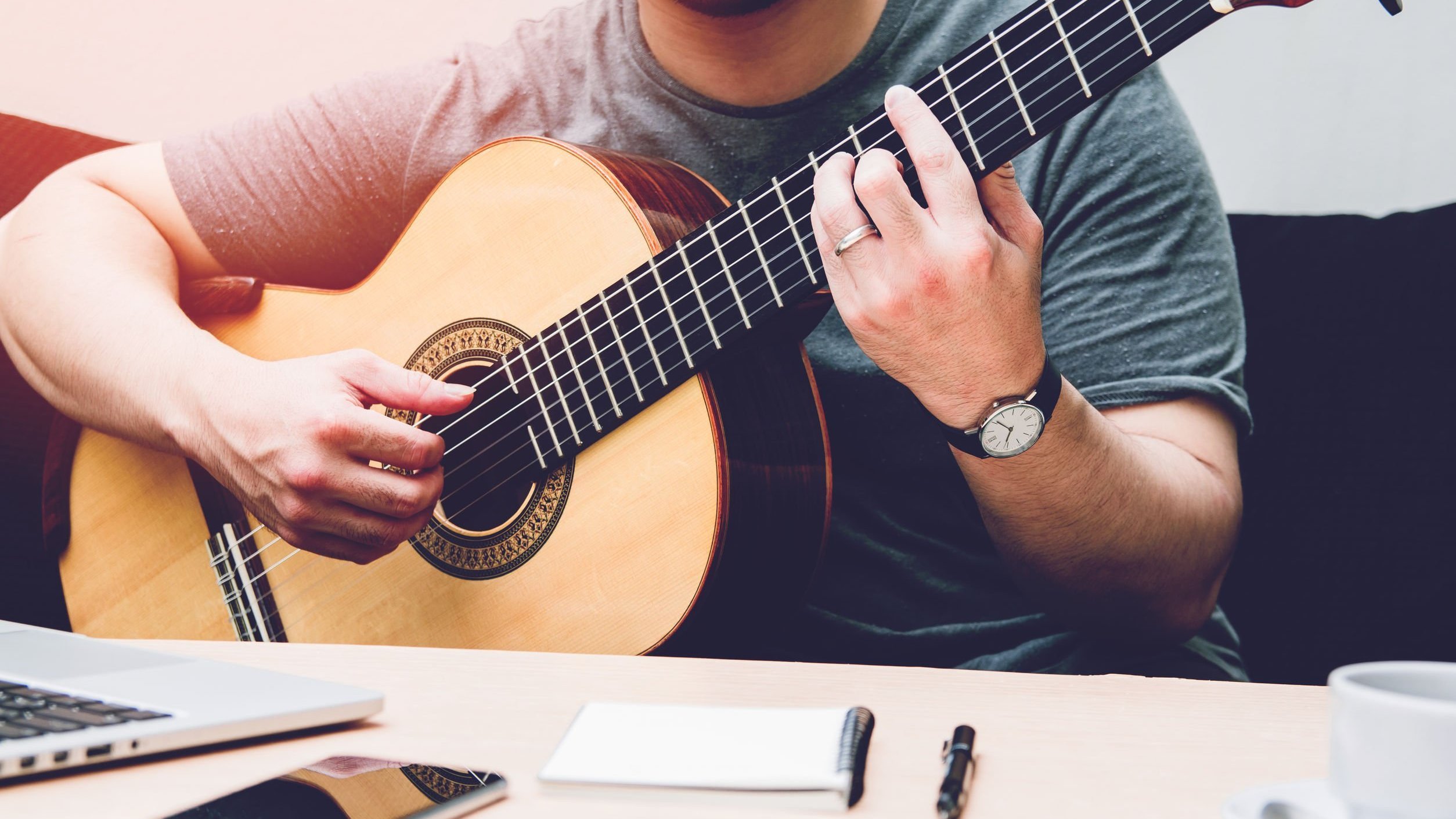 Homem branco segurando violão.