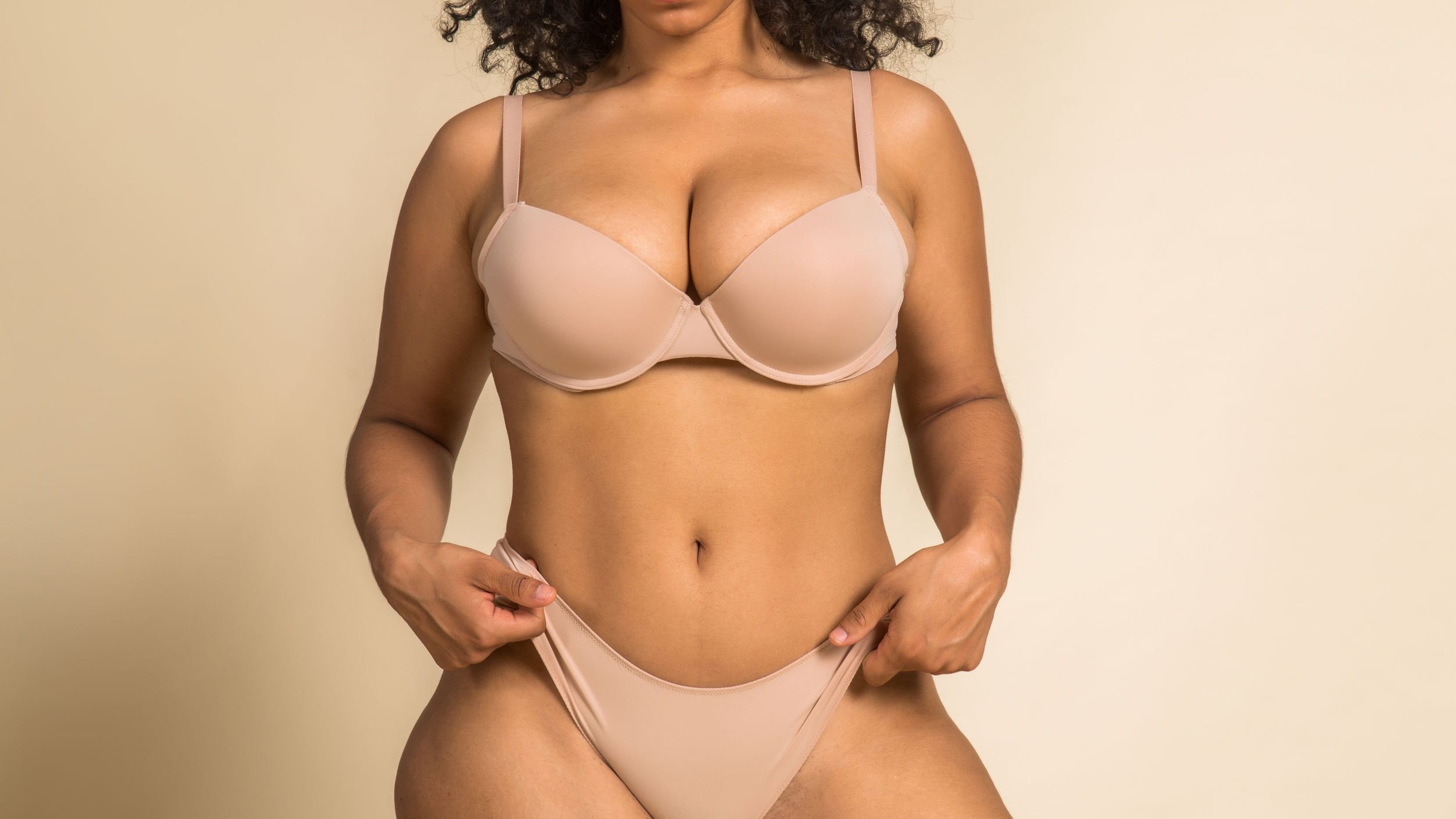 Corpo de mulher negra, usando lingerie bege.