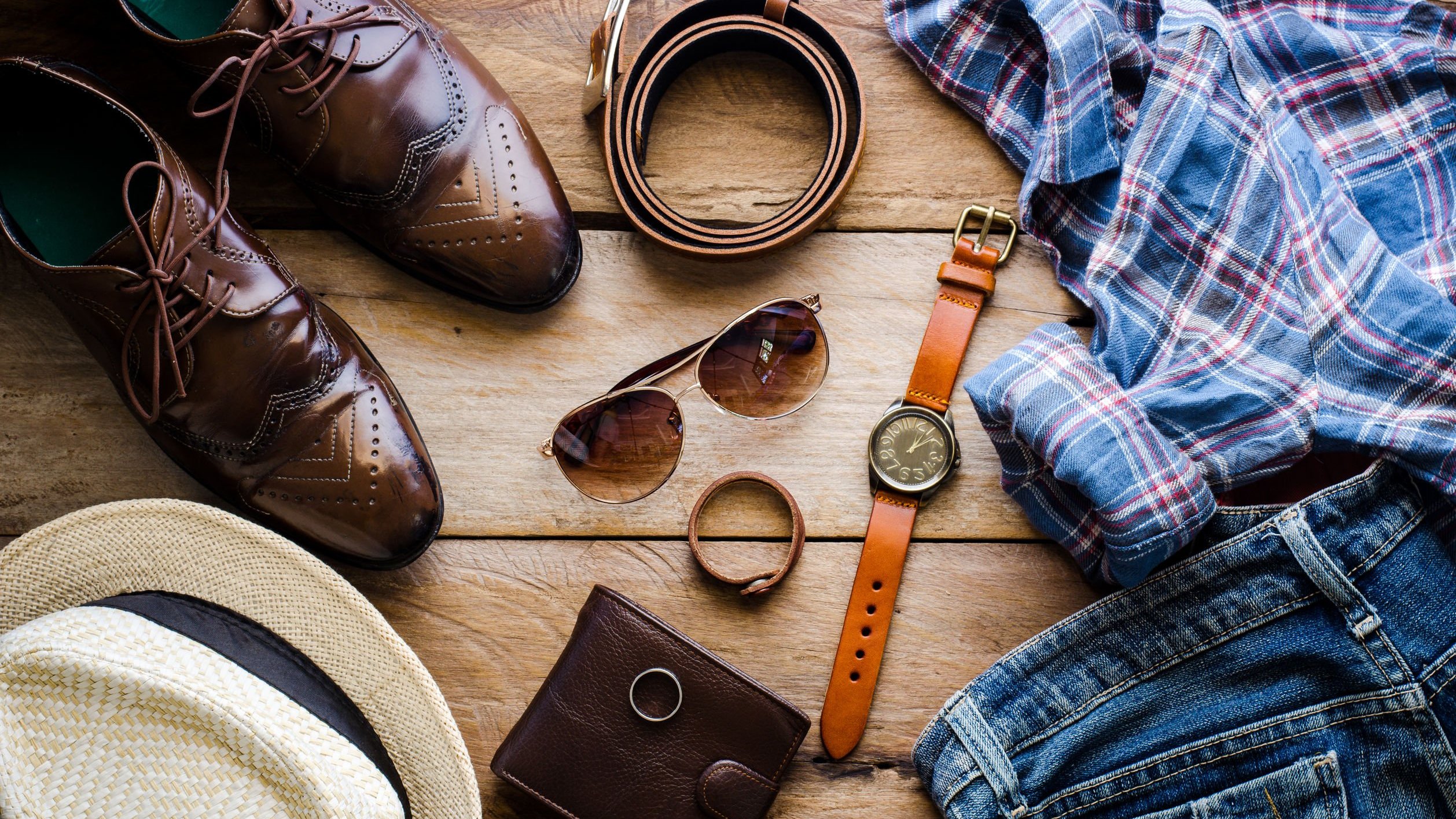 Acessórios masculinos como cinto, óculos escuro, relógio de pulso, sapatos, carteira e uma camisa.