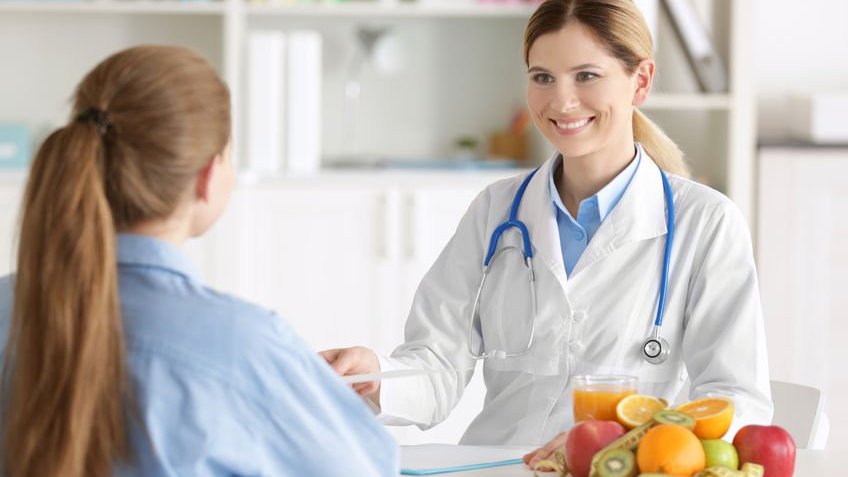 Nutricionista atendendo paciente e sorrindo