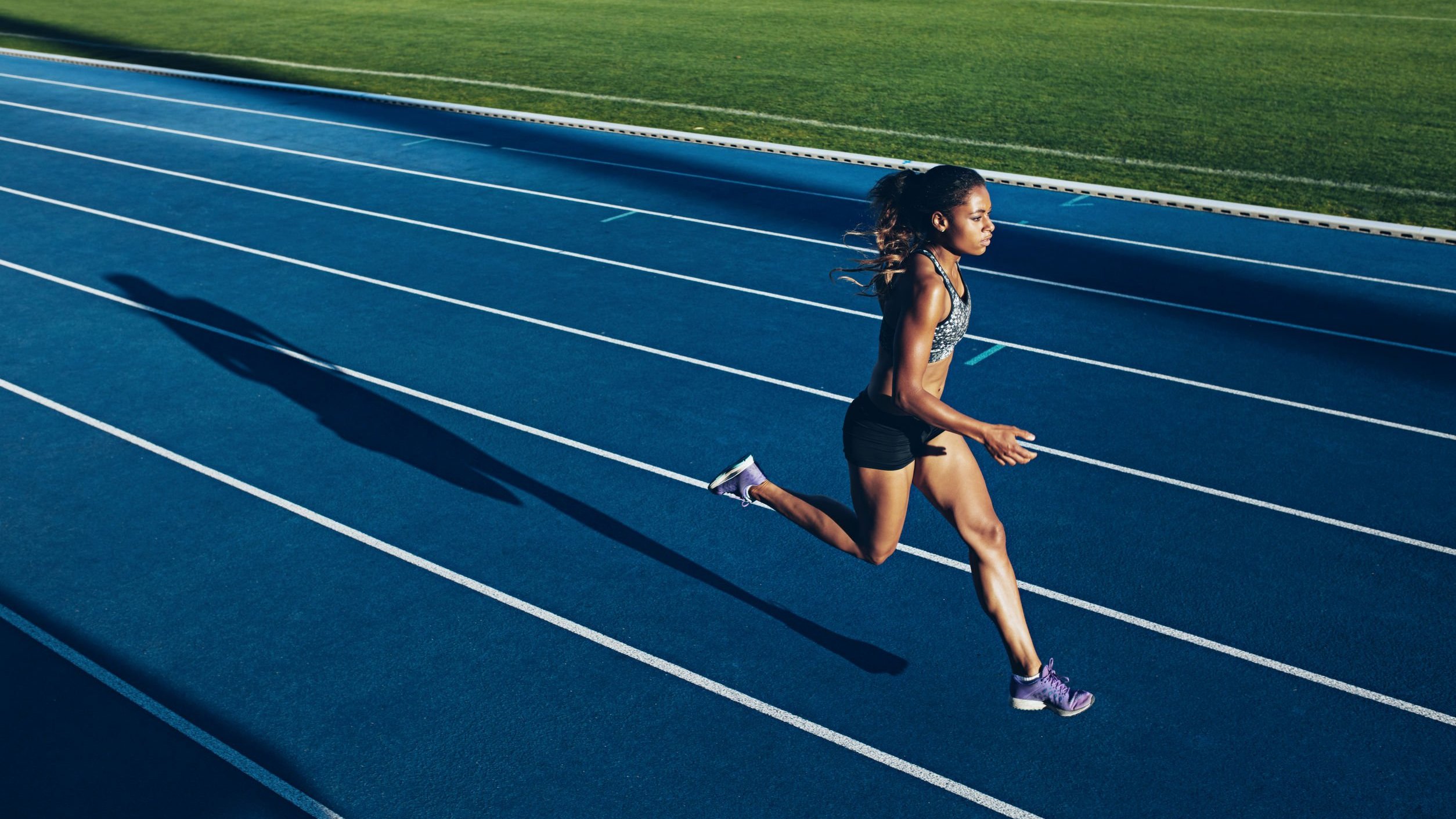 Mulher atleta correndo em pista de de corrida.