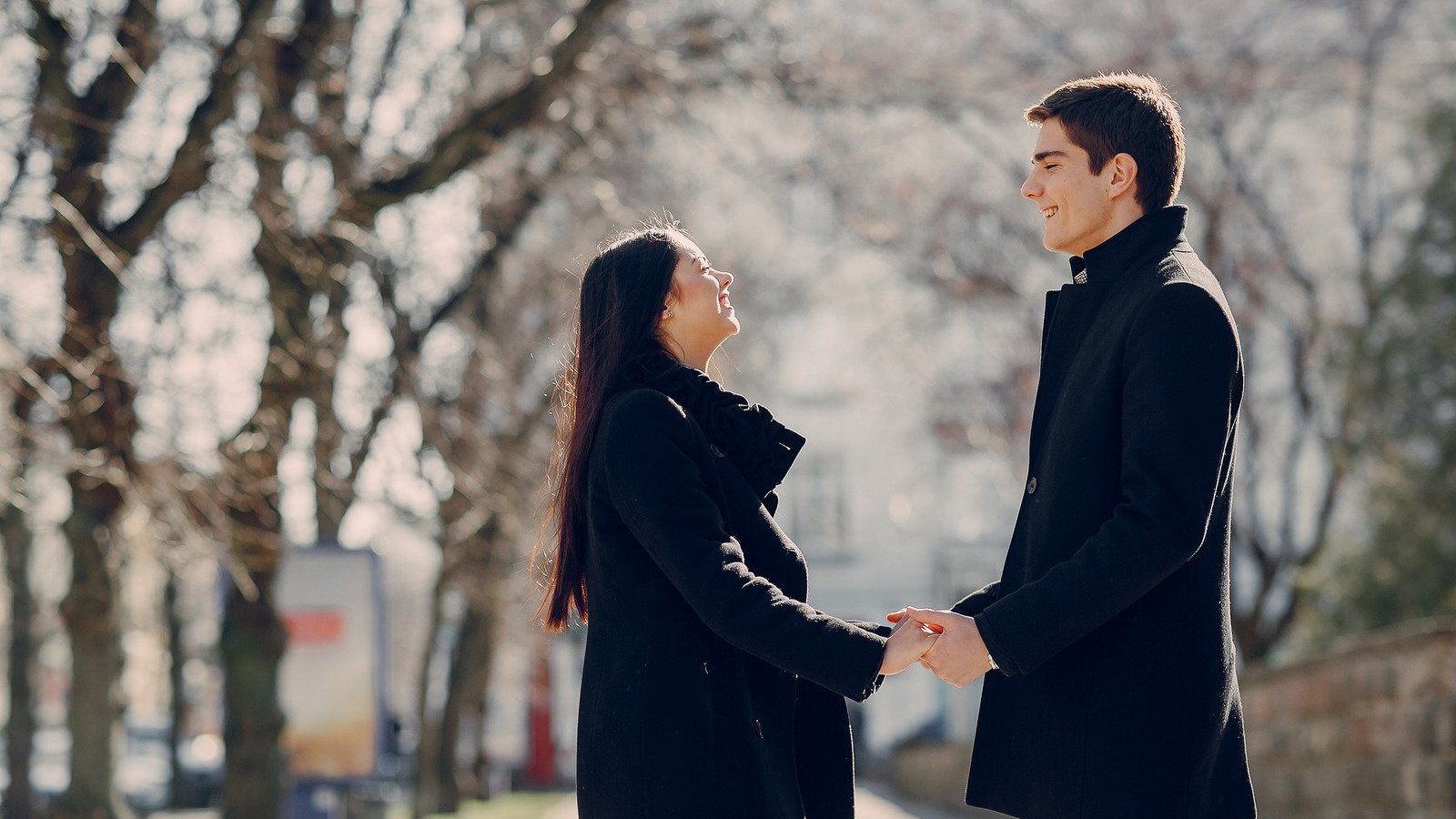 Homem e mulher brancos, de frente um para o outro, segurando as mãos.