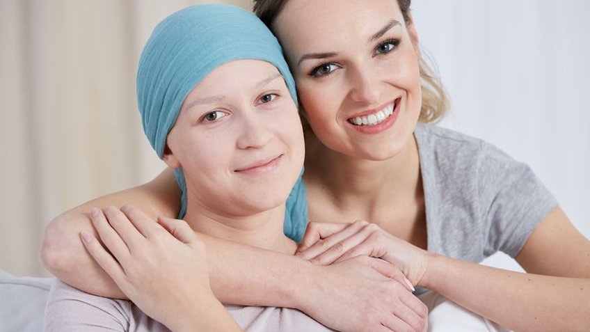 Mulher abraçando mulher com câncer
