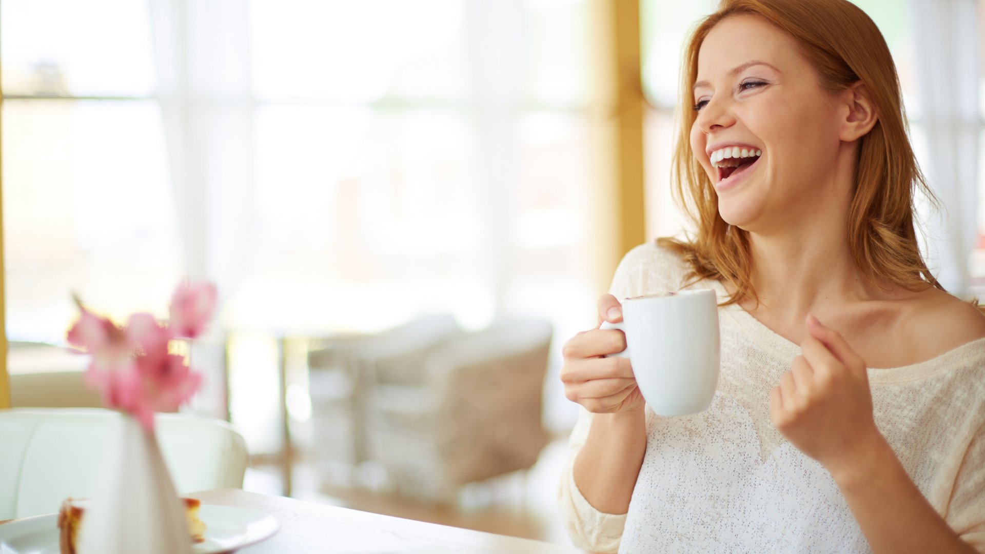 Mulher sorrindo com uma caneca branca na mão