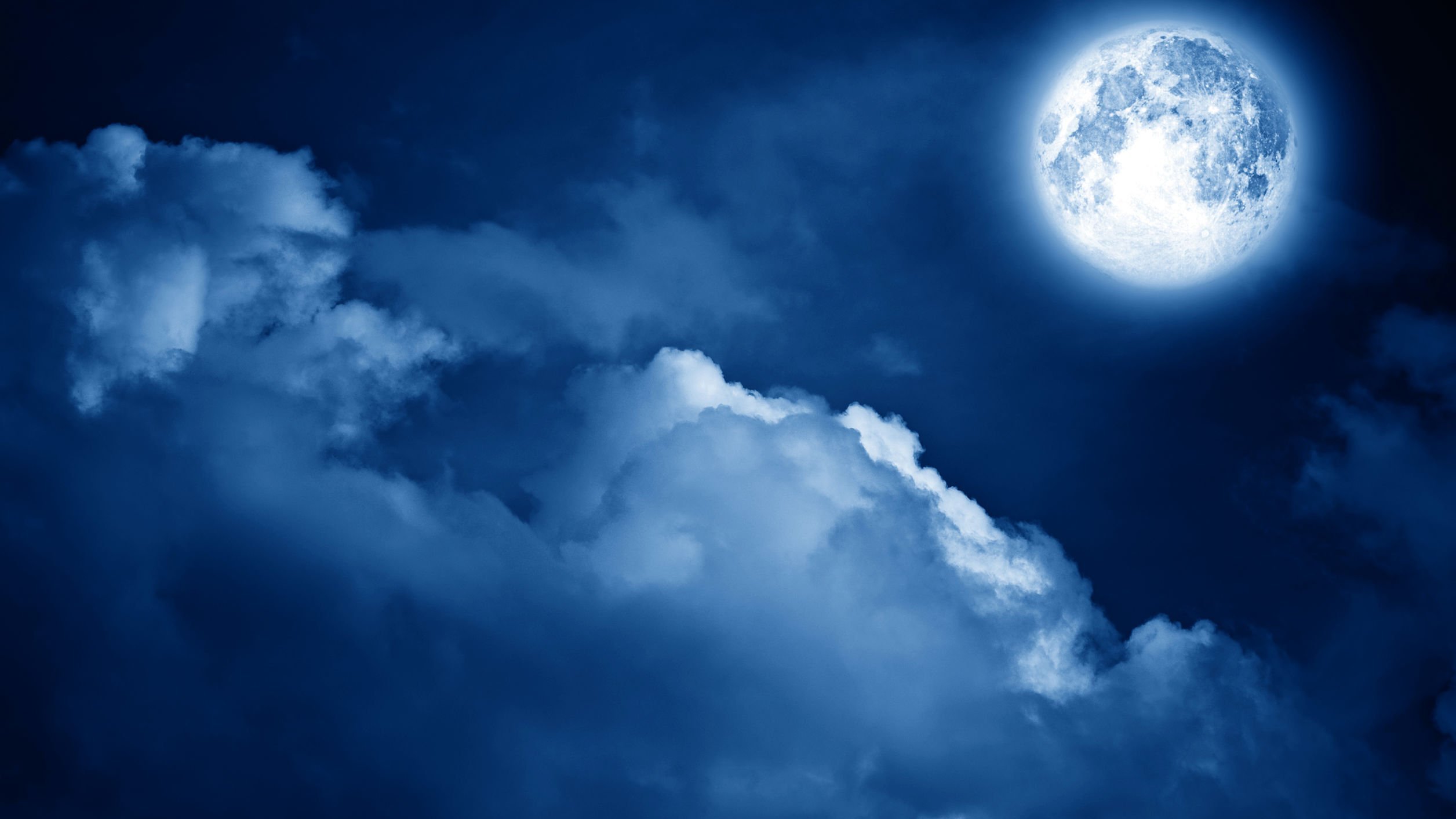 Céu durante a noite, com nuvens e a Lua bem próxima da Terra.