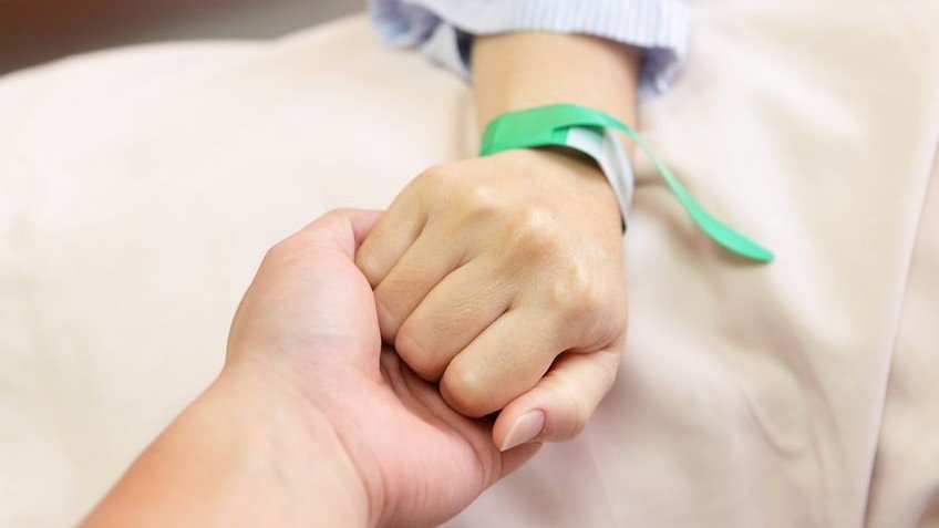 Marido segurando a mão de sua esposa no hospital