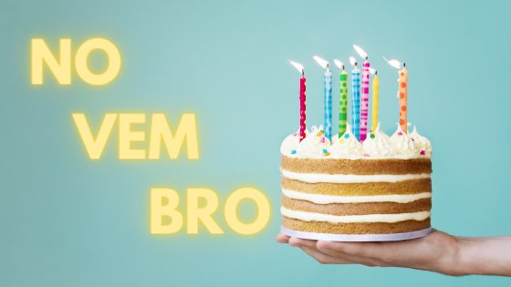Mão segurando bolo de aniversário com escrito 'Novembro' em amarelo