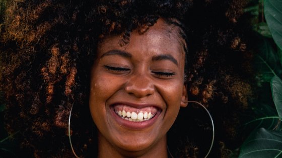 Mulher sorrindo de olhos fechados