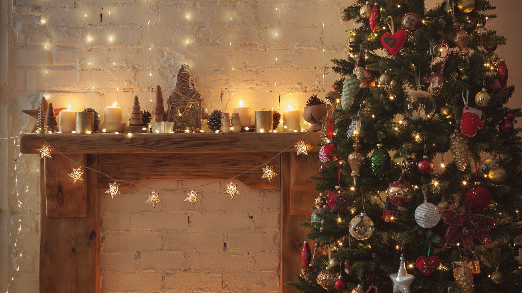 Árvore de natal ao lado de uma lareira com velas e luzes