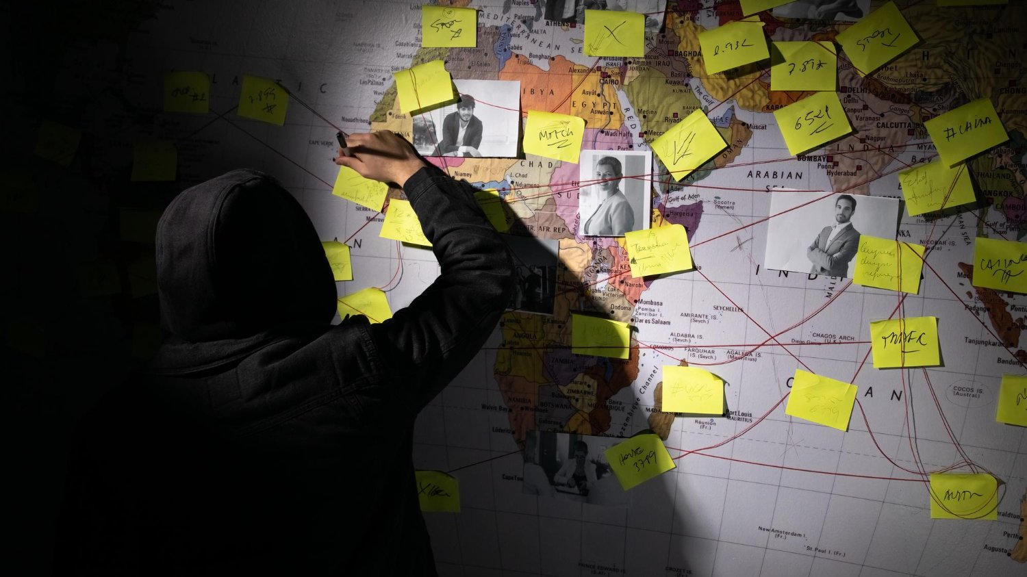 Homem juntando pistas em um mapa mundi com anotações e fotos