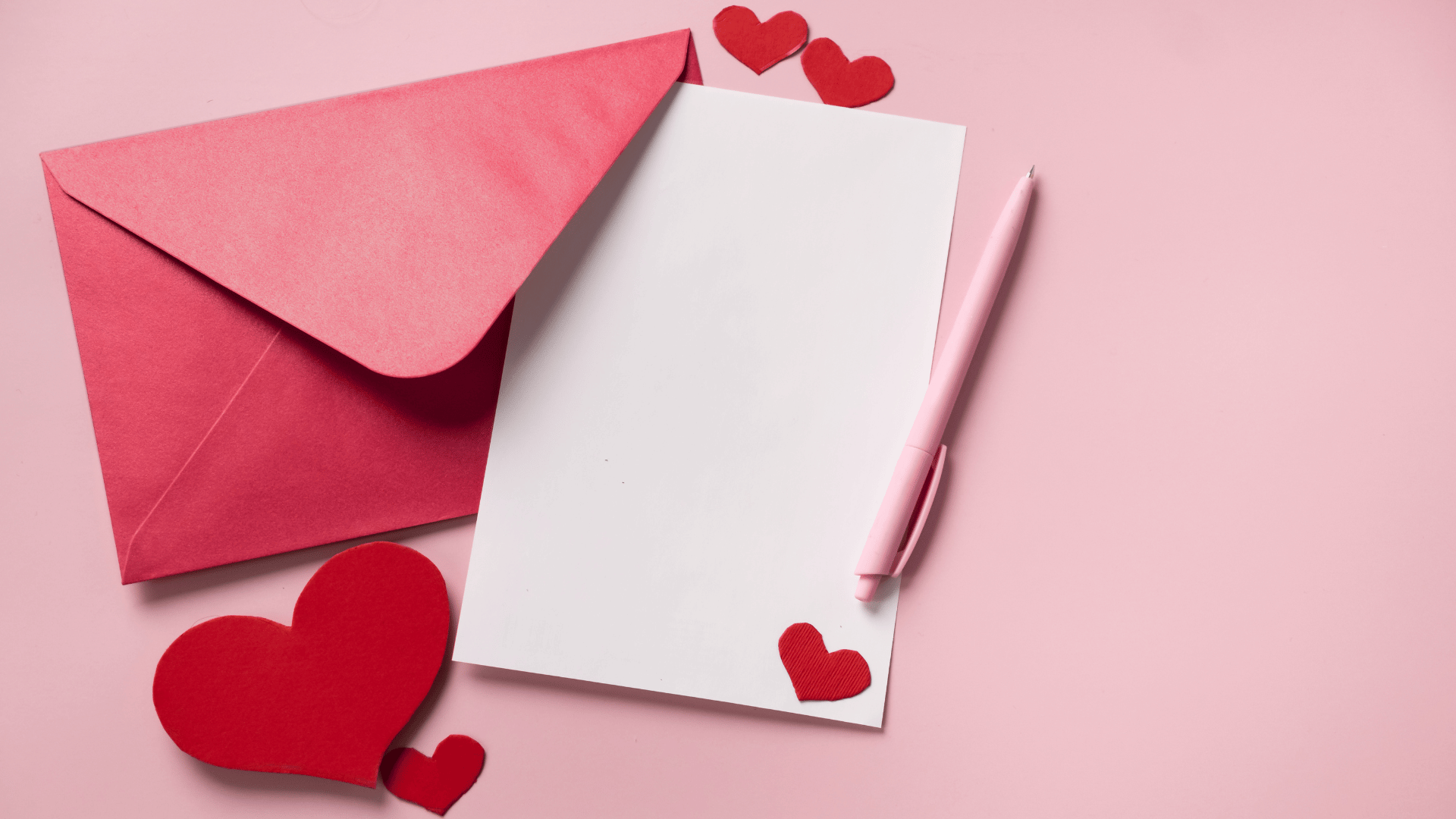 Ume envelope com um papel e uma caneta em tons de rosa com corações.