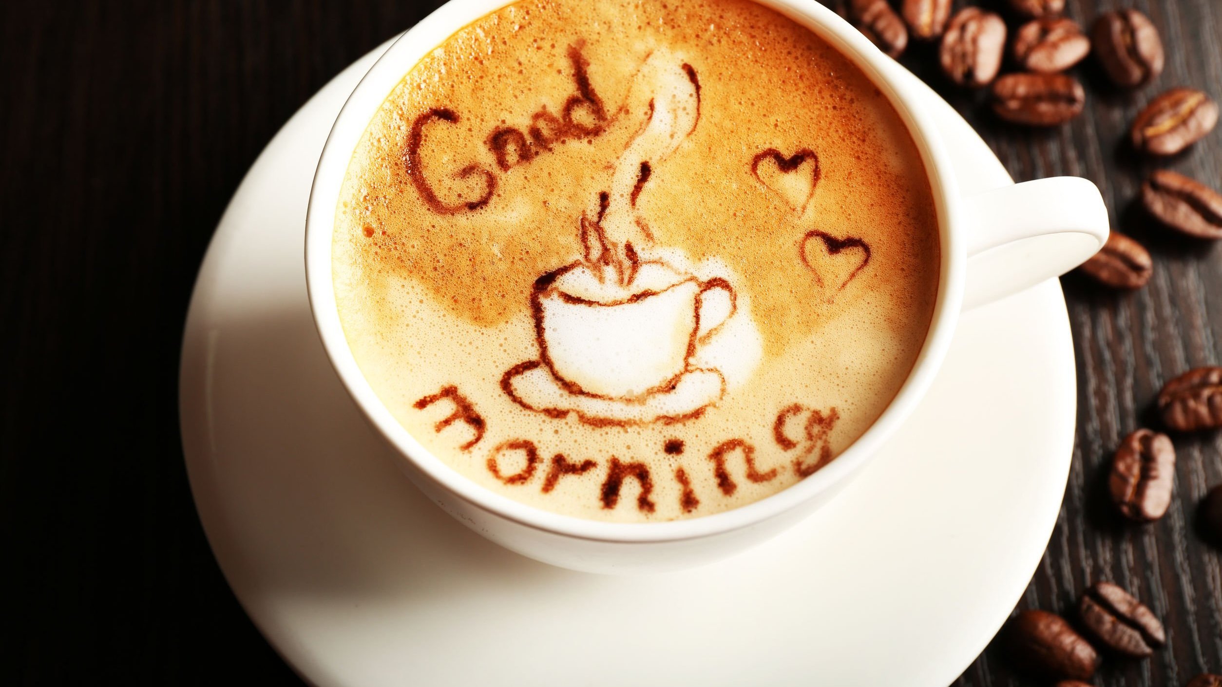 Xícara de café com desenho na espuma escrito Bom Dia, em inglês.