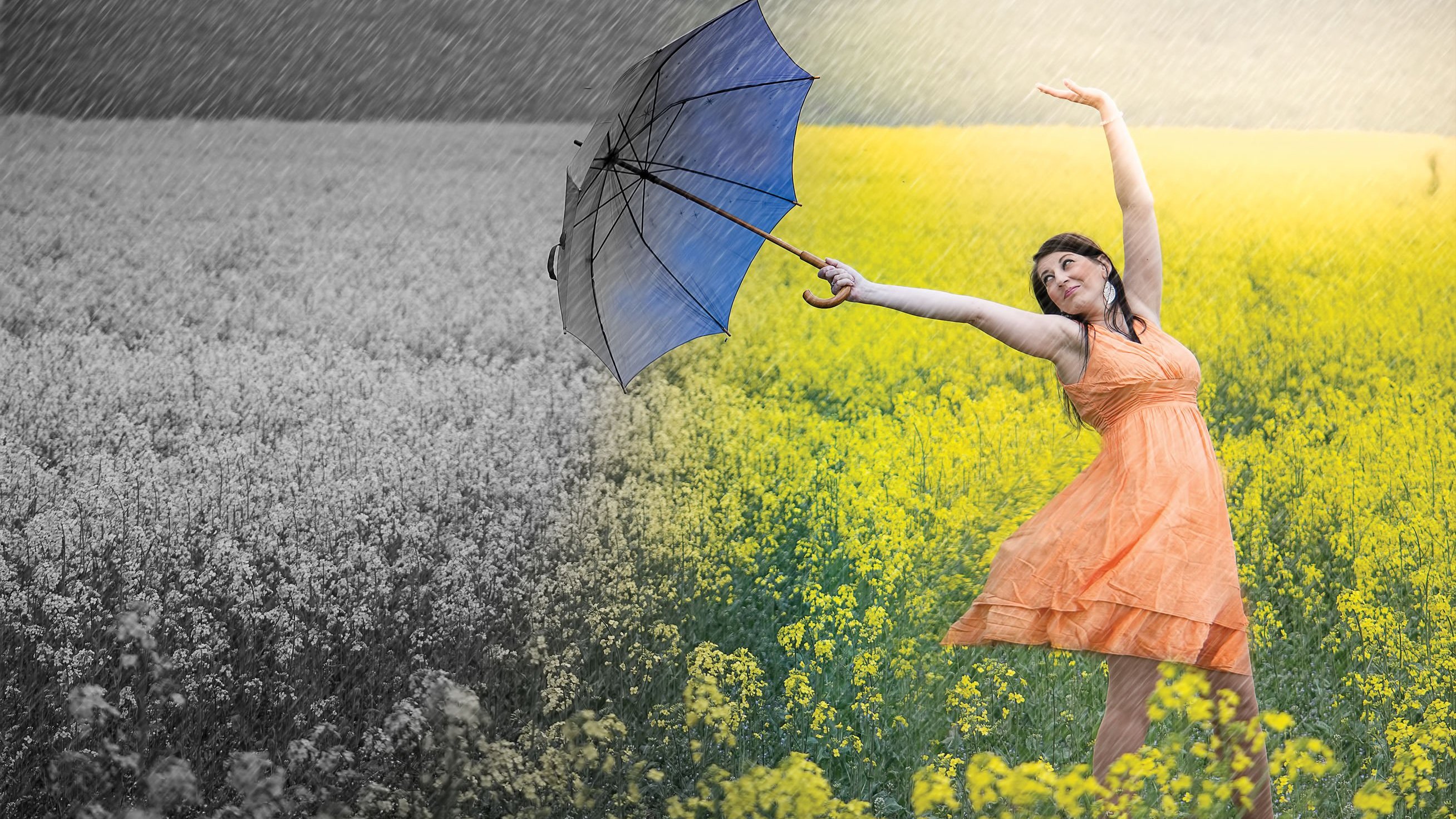 Mulher dançando com o guarda chuva pelo campo florido
