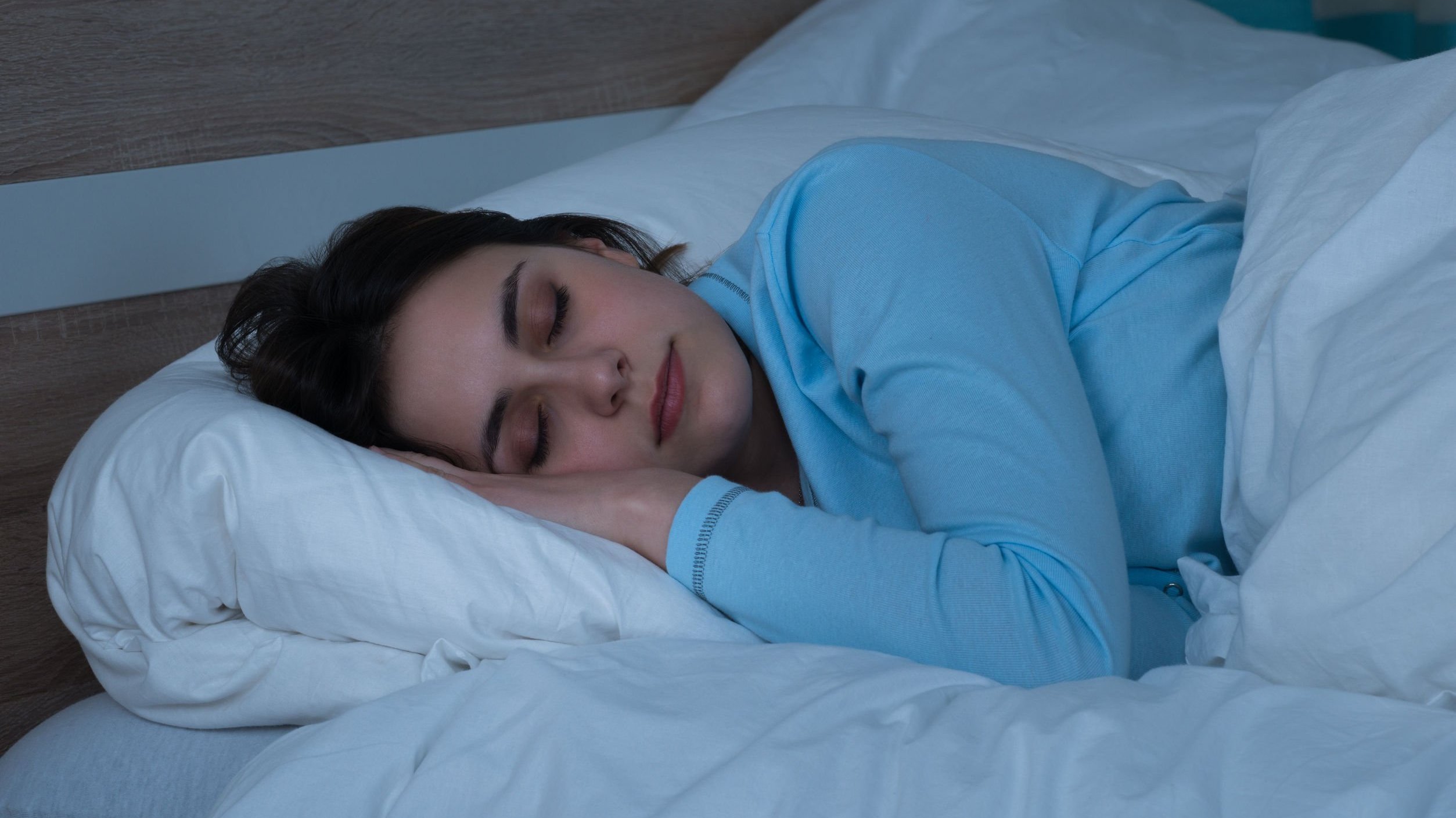 Mulher deitada na cama, dormindo.