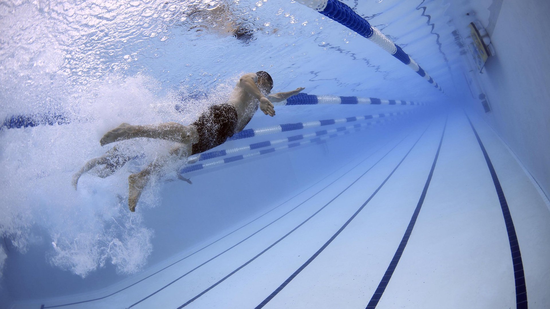 Homem nadando em uma piscina. A foto foi tirada do fundo