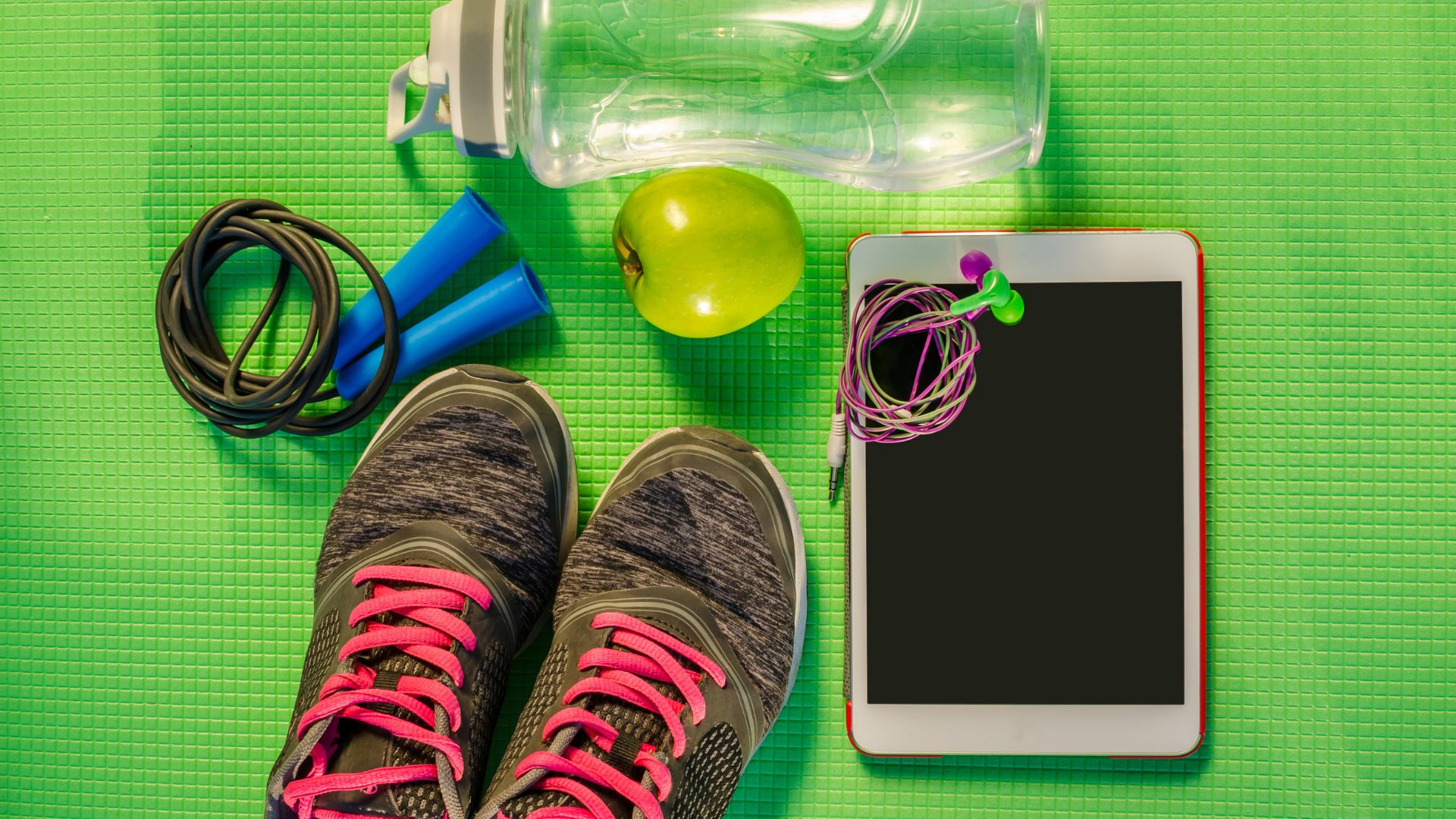 Olena_Z / Getty Images / Canva Celular, fone de ouvido, corda de pular, tênis, garrafa d'água e uma maçã verde