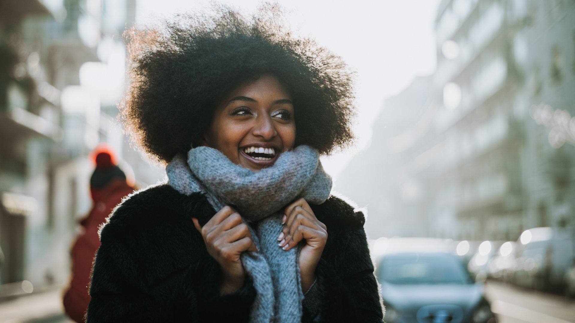 Mulher sorridente de cachecol andando na rua durante o inverno