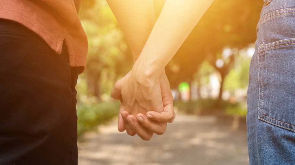 CravenA / Shutterstock.com Casal de mãos dadas em um parque
