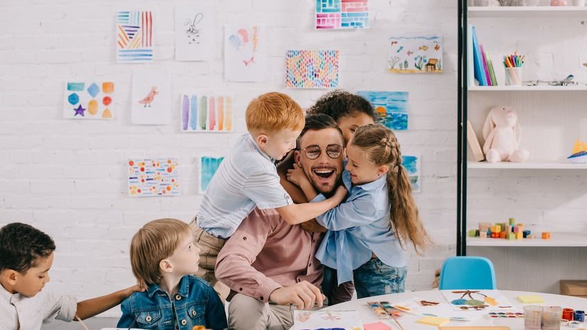 Professor com crianças em sala de aula sorrindo