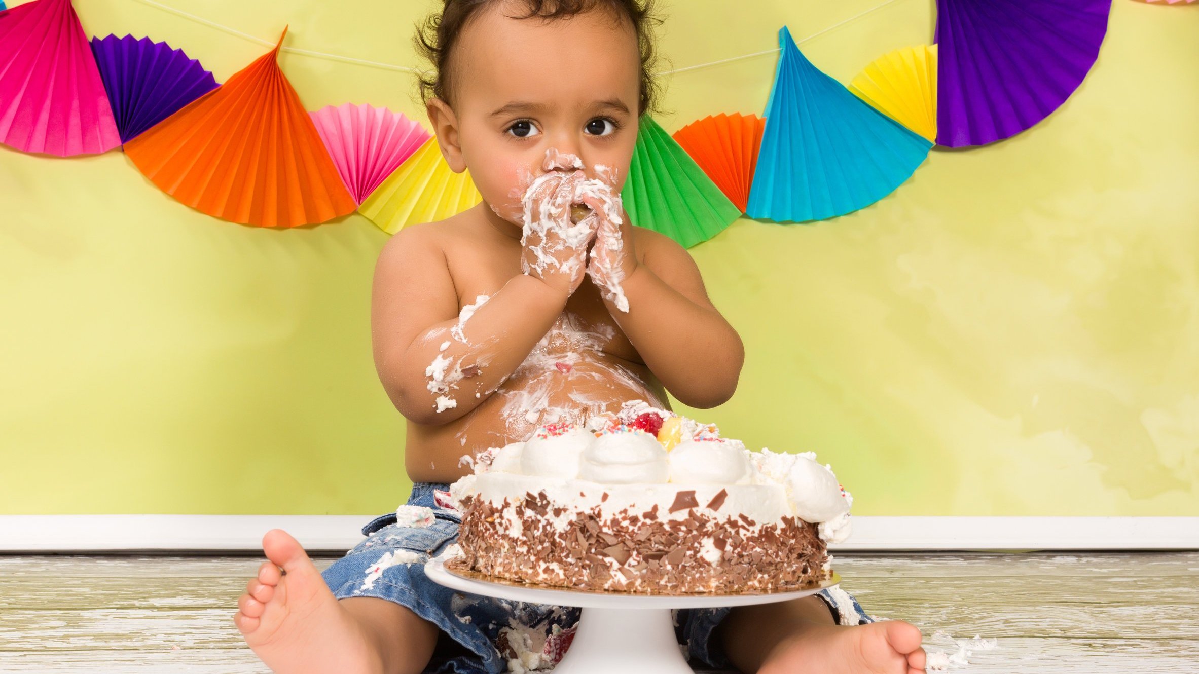 Bebê se sujando com um bolo de aniversário