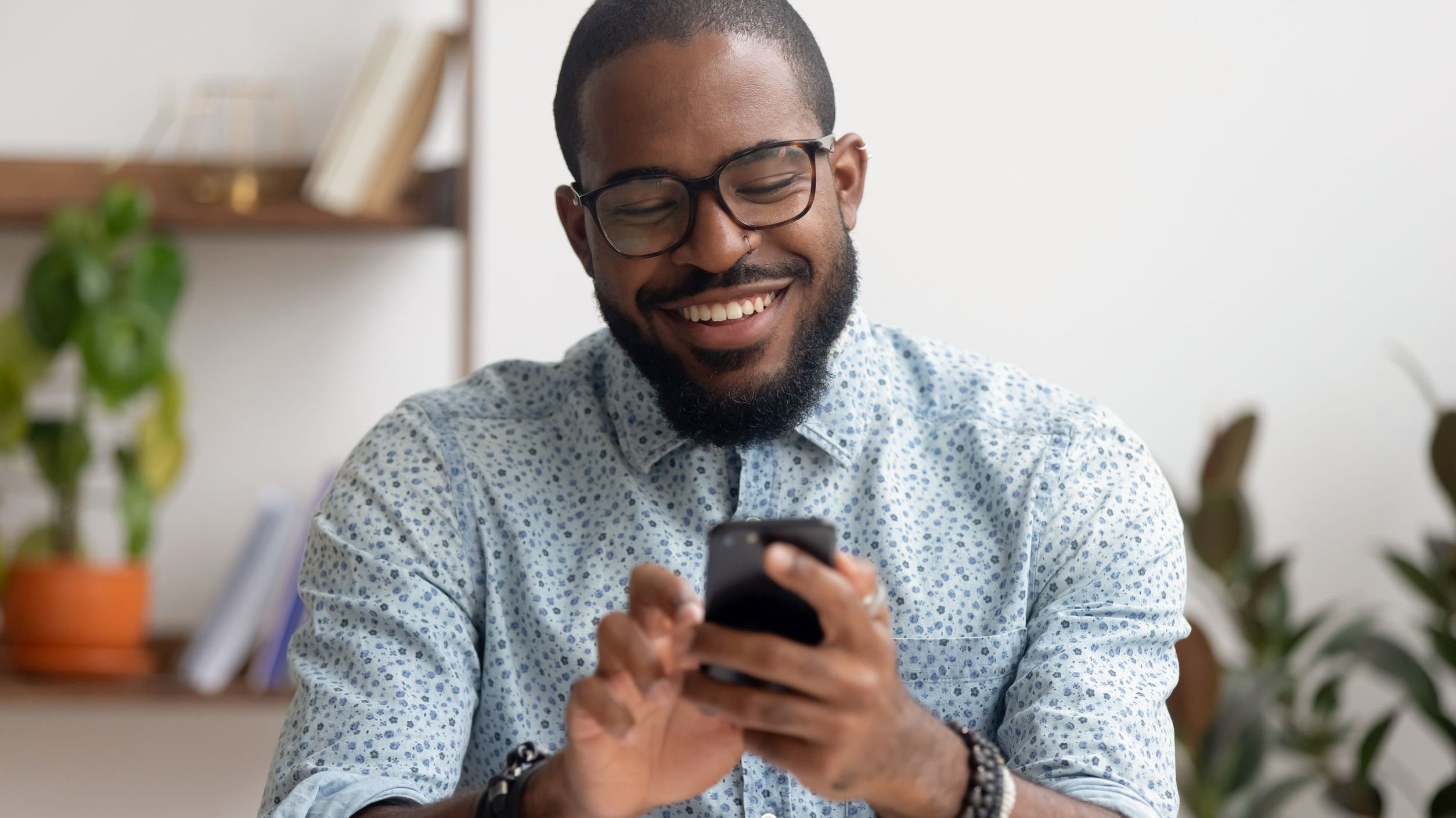 Homem sorri enquanto digita em celular.