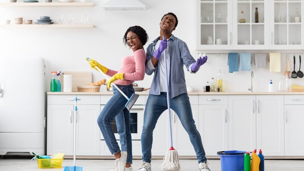 Casal limpando a casa e brincando com os utensílios de limpeza