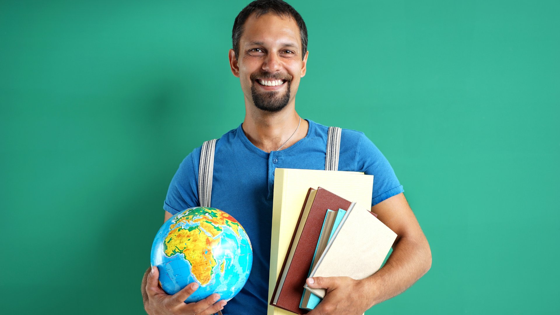 Homem sorrindo segurando globo terrestre e livros