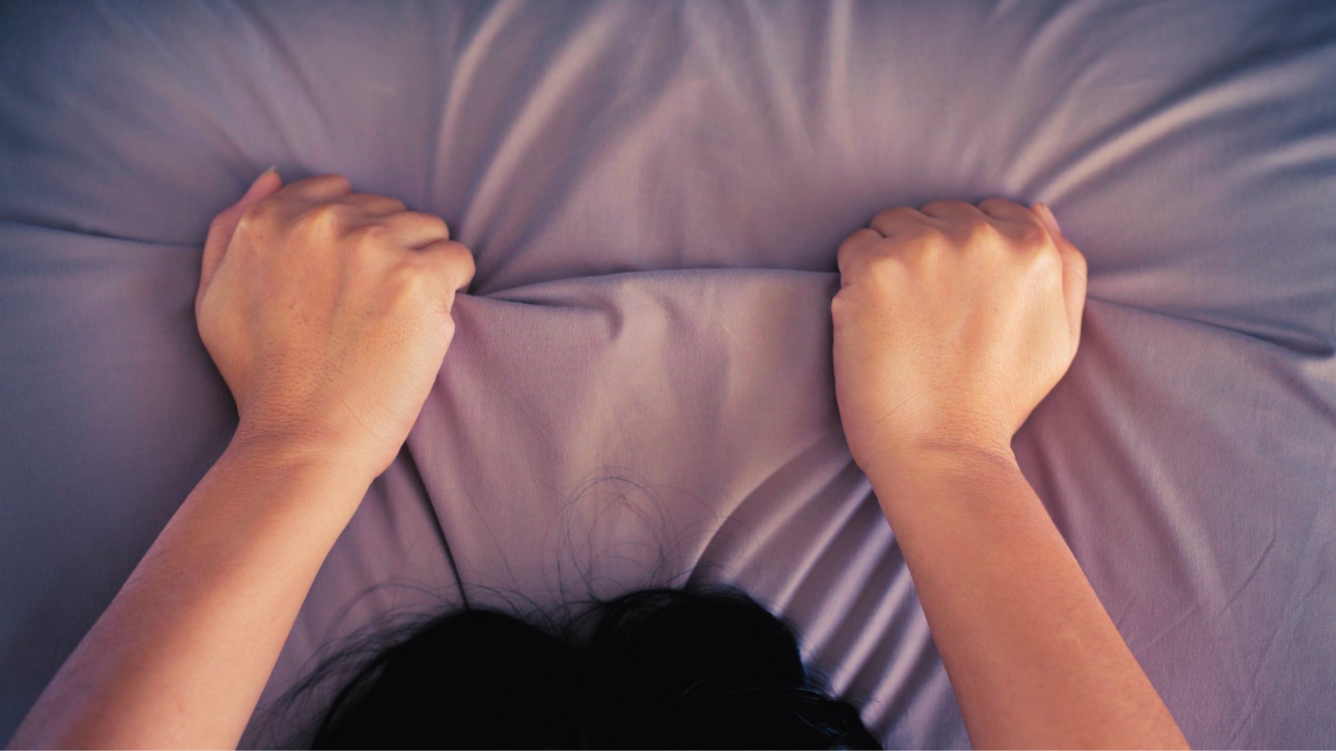 Mão de pessoa segurando o lençol da cama