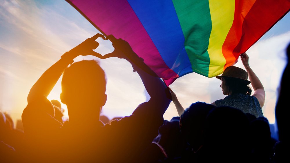 Pessoas segurando bandeira do Orgulho Gay