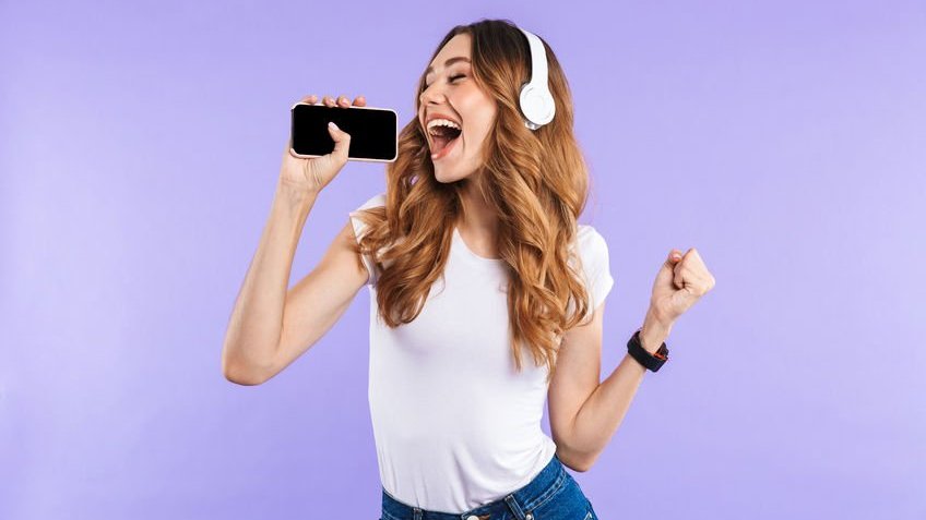 Dean Drobot / 123rf Menina com fone de ouvido e celular na mão.