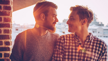svetikd / Getty Images Signature Casal gay se olhando com um sol atrás