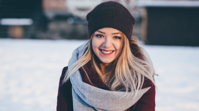 Menina sorrindo enquanto utiliza um look quente para o inverno