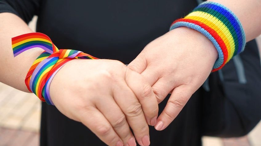 Mãos femininas com pulseiras que representam o movimento LGBT