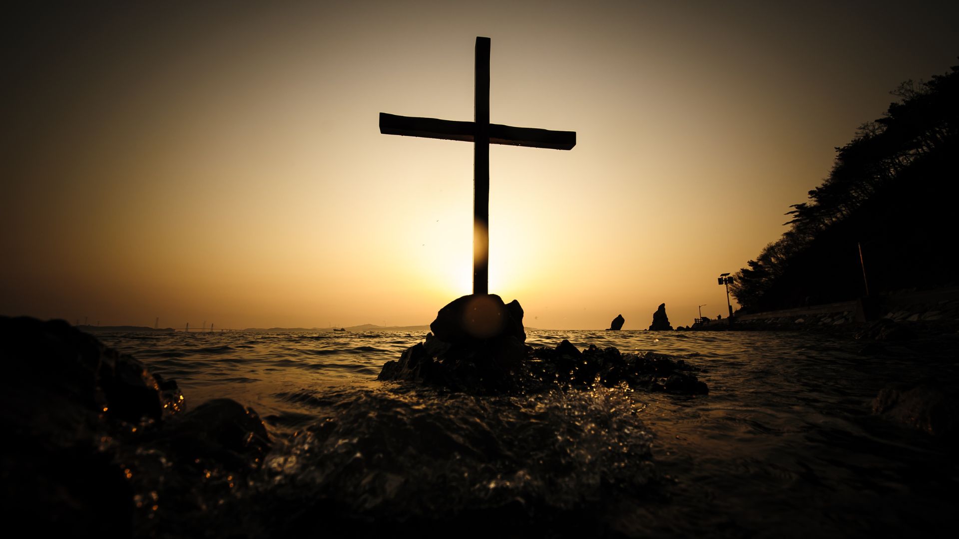 Imagem de uma cruz e atrá o pôr-do-sol