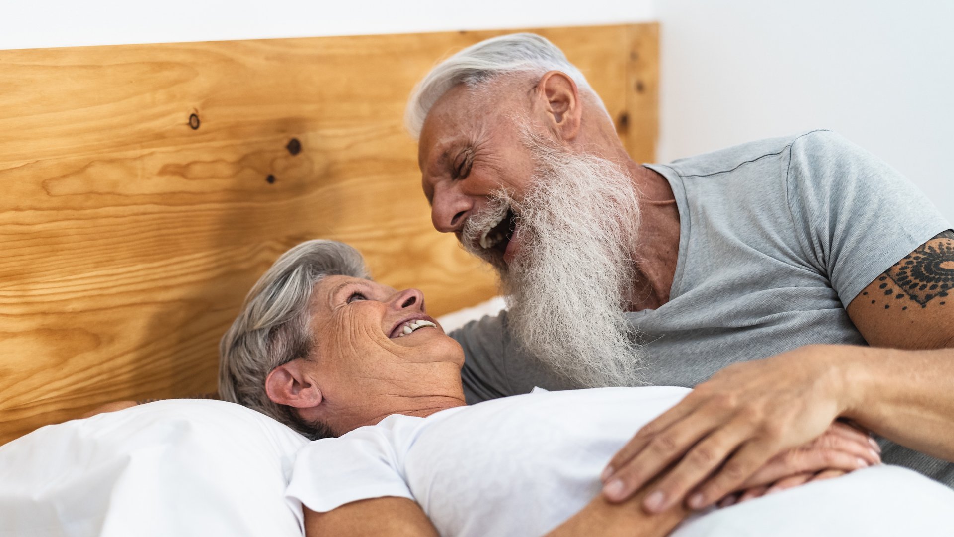 casal de idosos rindo na cama